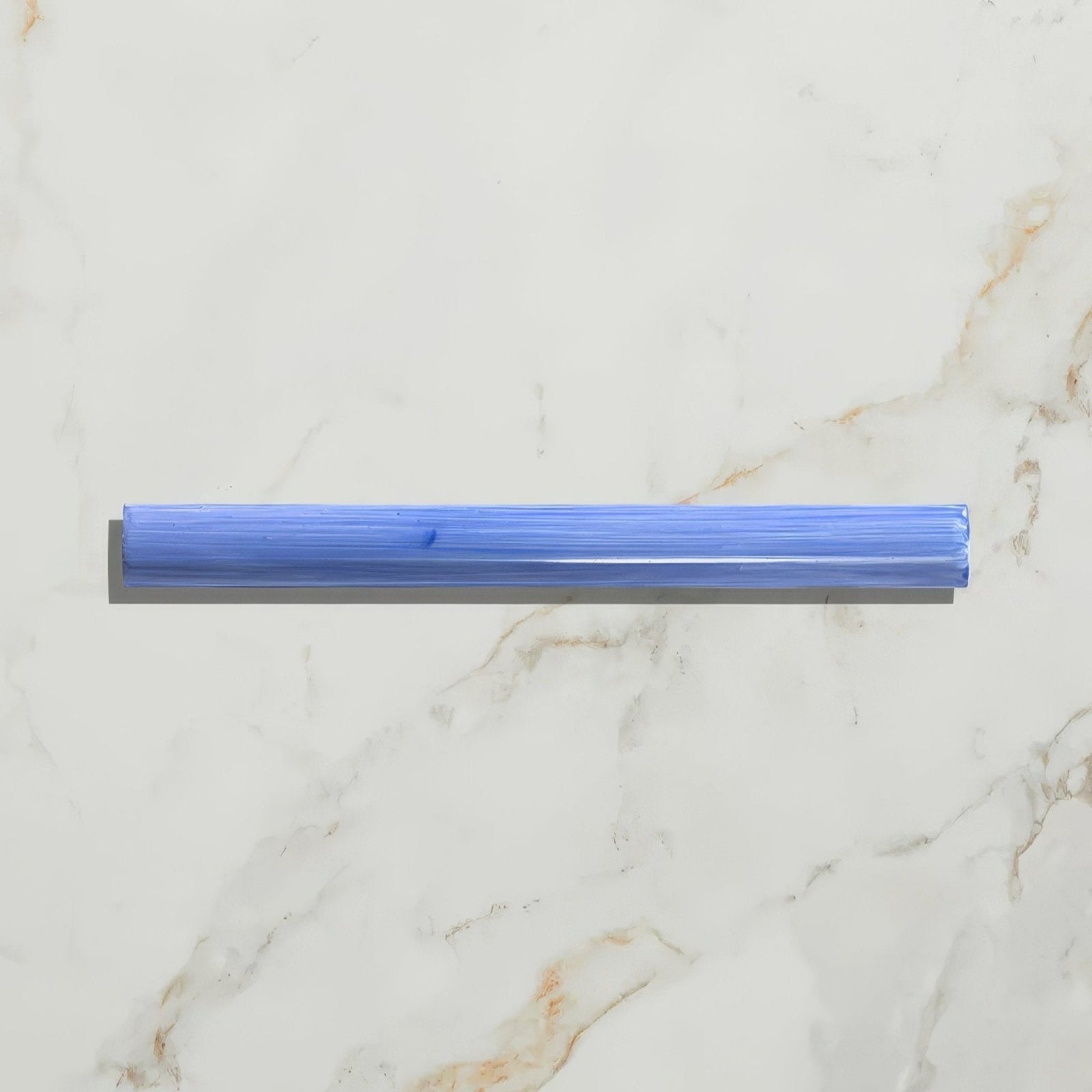 A translucent blue plastic straw with a textured surface and rounded edges featured in studio jamboree handpainted ceramic greek blue beading