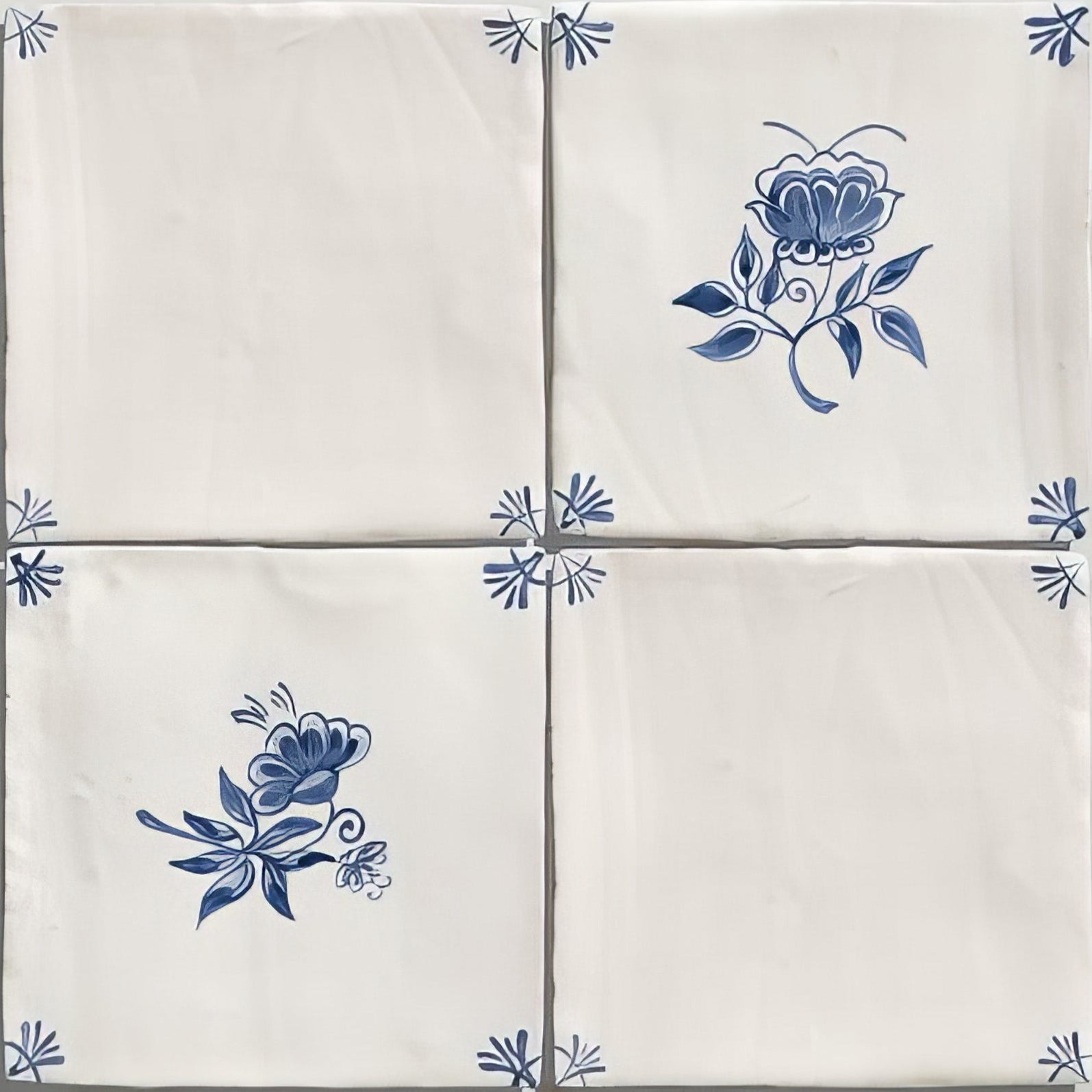 Four cream-colored ceramic tiles with delicate blue floral and leaf patterns from studio nonnas kitchen classica ceramic