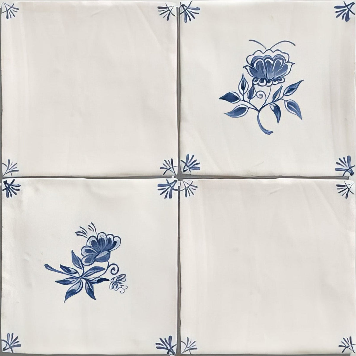 Four cream-colored ceramic tiles with delicate blue floral and leaf patterns from studio nonnas kitchen classica ceramic