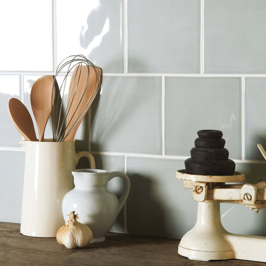 Cream-colored ceramic pitcher holding wooden spoons and metal whisk in Sudbury Field Tile setting