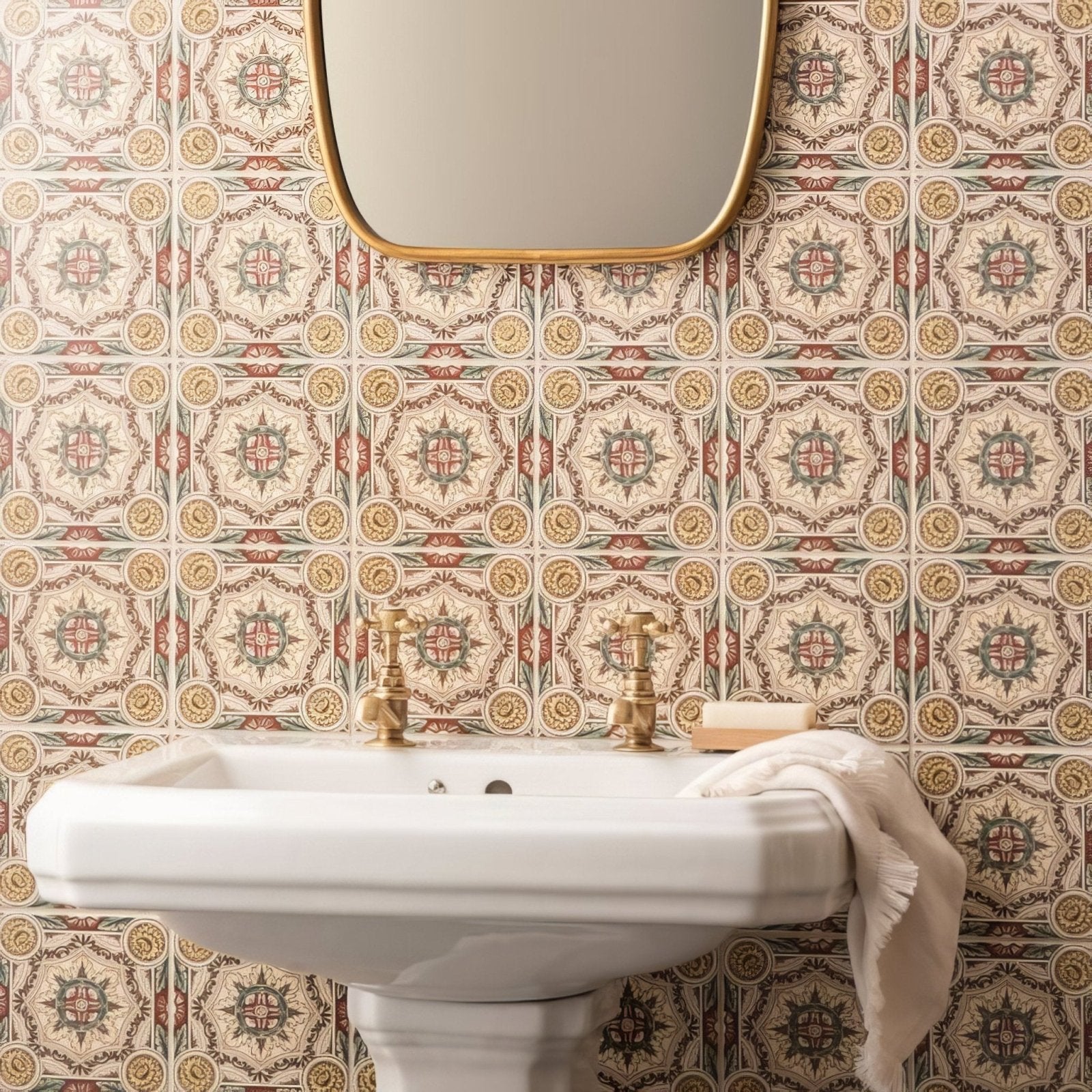 White ceramic pedestal sink with gold-toned faucets on symmetrical floral pattern single tile in county white