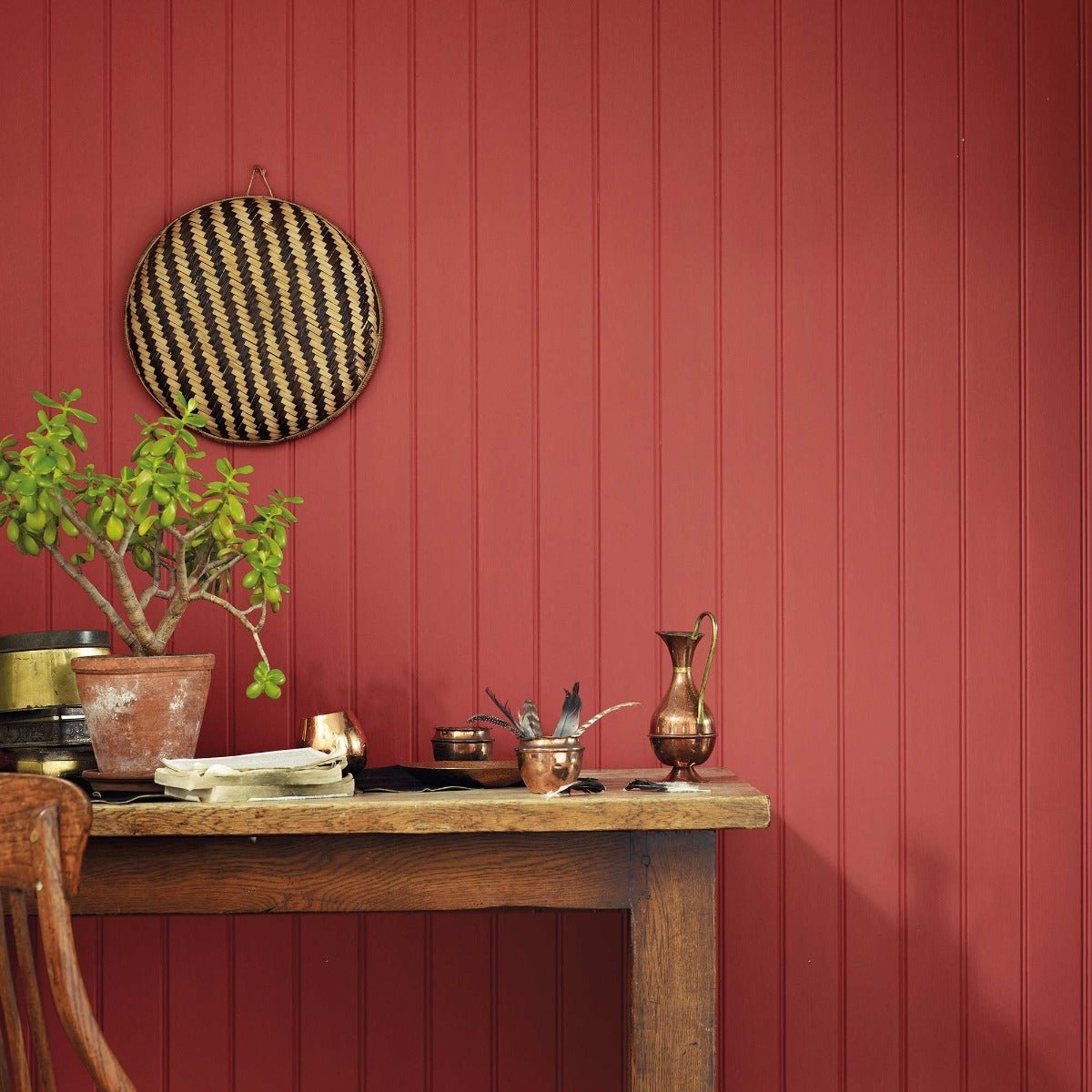 Terracotta warrior round woven basket with black and beige diagonal stripes hanging on red paneled wall