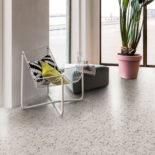 White wireframe chair with black and yellow patterned cushions styled with terrazzo small vinyl tiles flooring