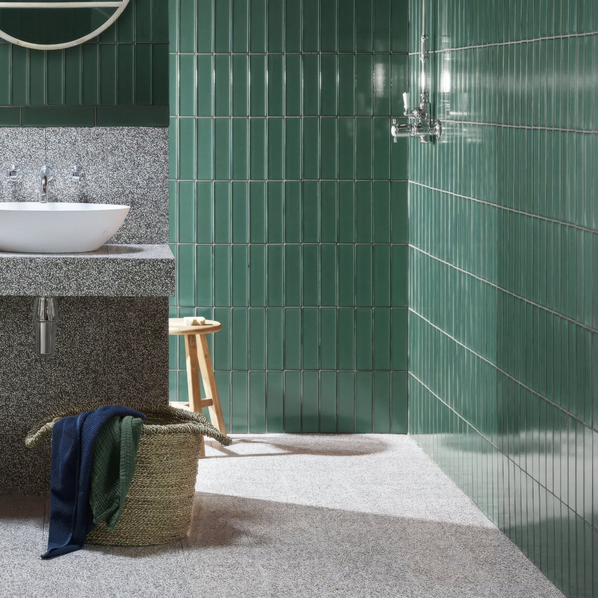 Emerald green glossy vertical subway tiles lining bathroom walls in terrazzo marini base design