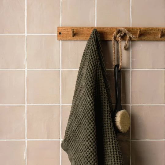 Olive green waffle weave towel hanging from wooden rack showcasing thatch field tile texture and color