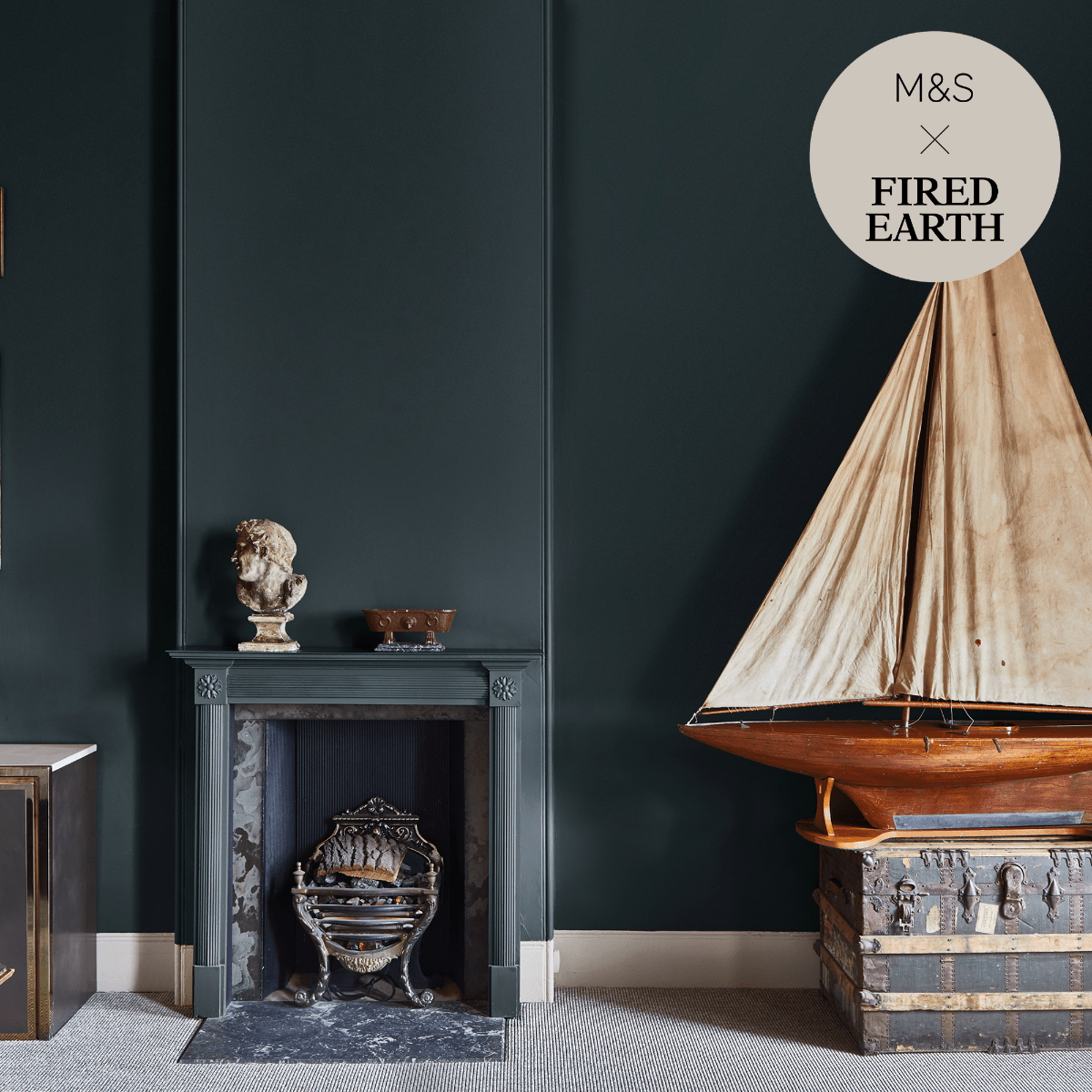 A vintage-style wooden model sailboat with beige sails resting on an antique trunk under the wave collection