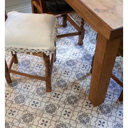 White knitted cushion with tassel trim on wooden stool beside urban callizo patterned porcelain tile