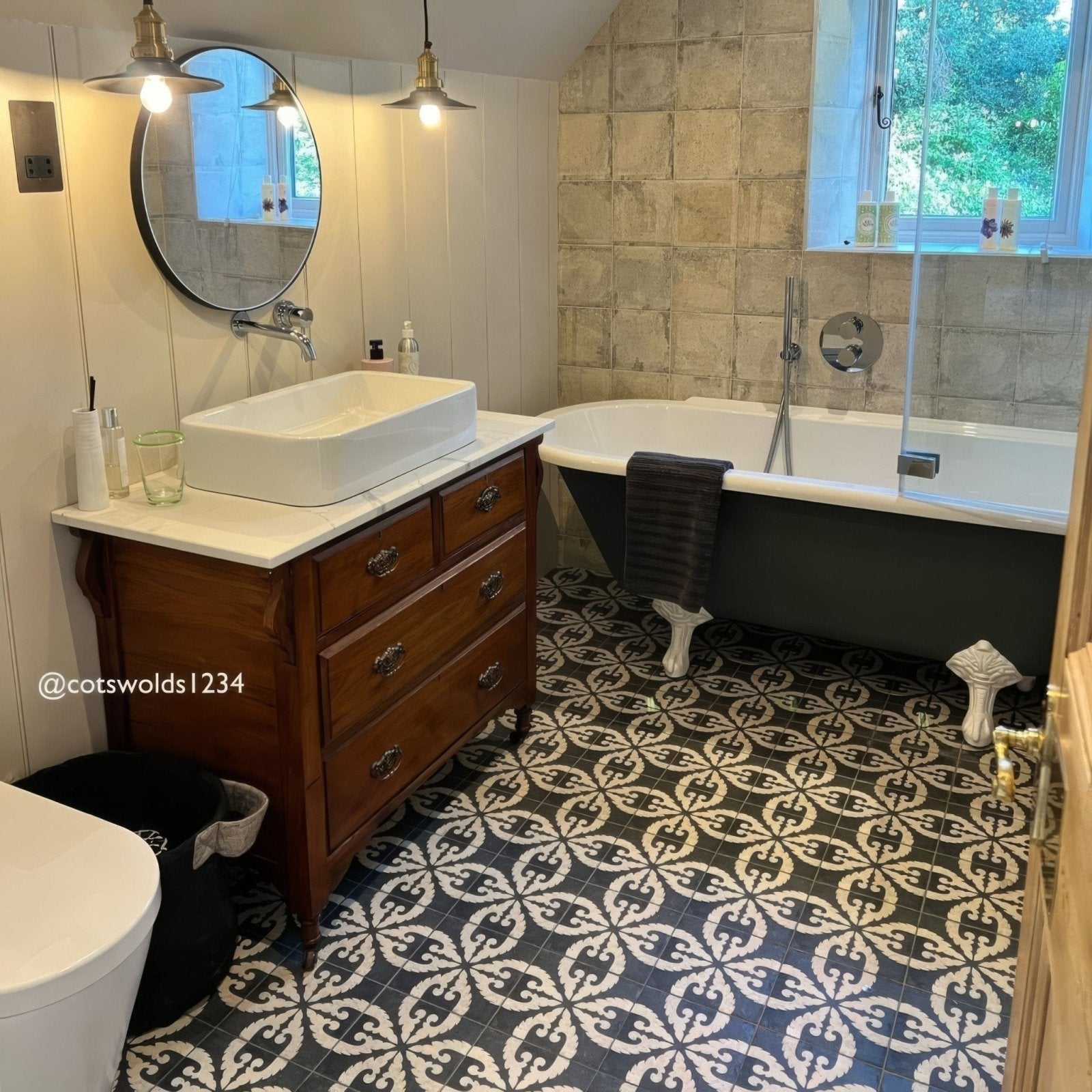 Black clawfoot bathtub with white porcelain feet and chrome faucet on urban velasco patterned porcelain tile floor