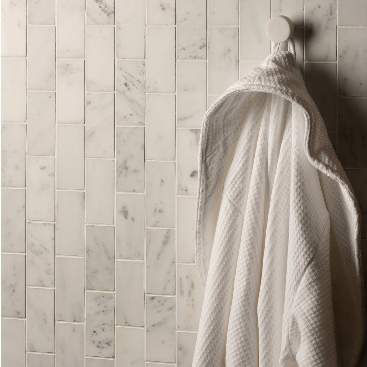 Viano White Honed Brickbond Mosaic white marble brick mosaic with a white waffle-weave bathrobe