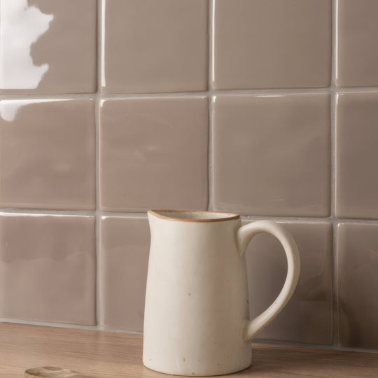 Cream-colored ceramic pitcher with subtle brown rim and matte finish featured on walnut field tile background