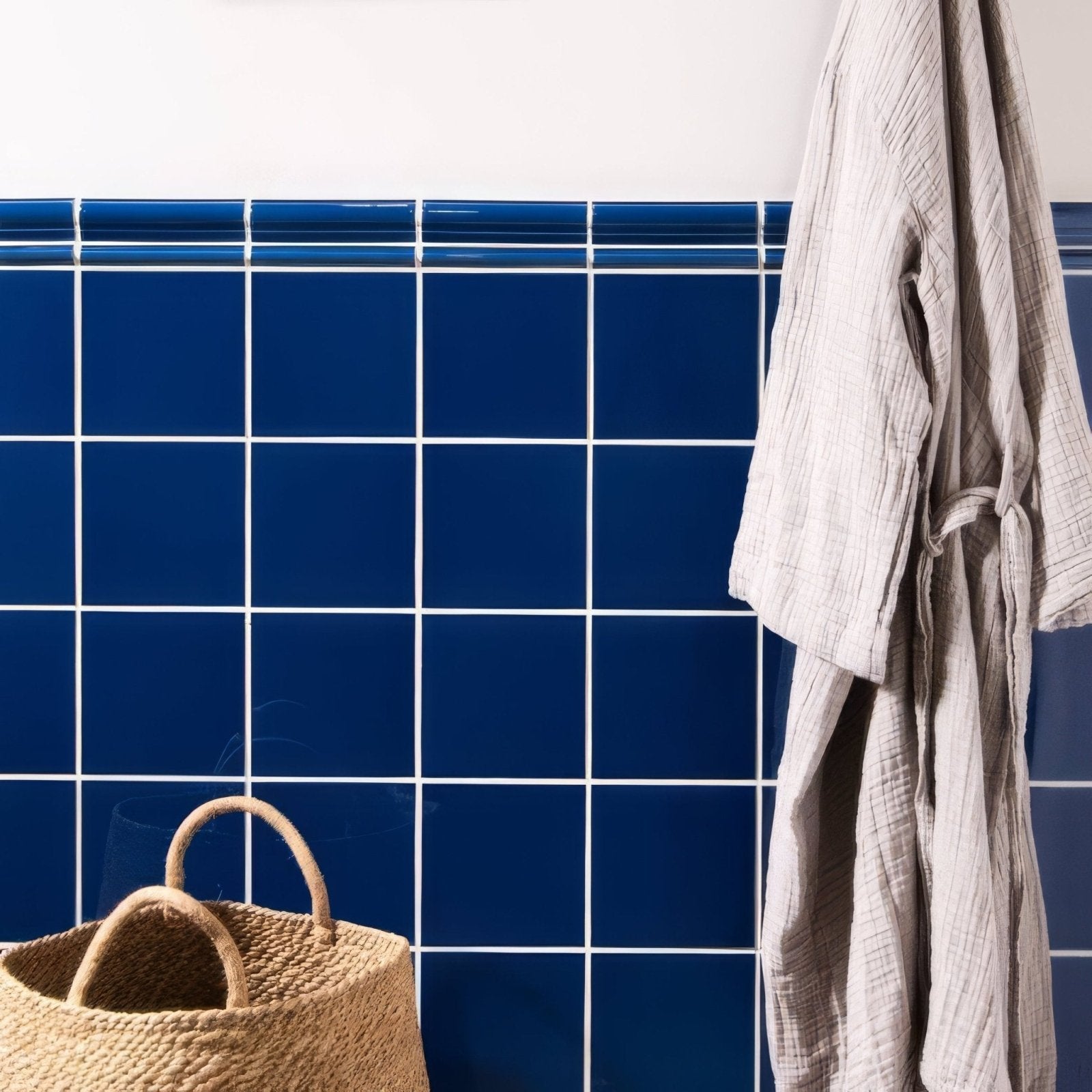 A woven beige basket with rounded handles against a vibrant blue Windsor blue field tile background