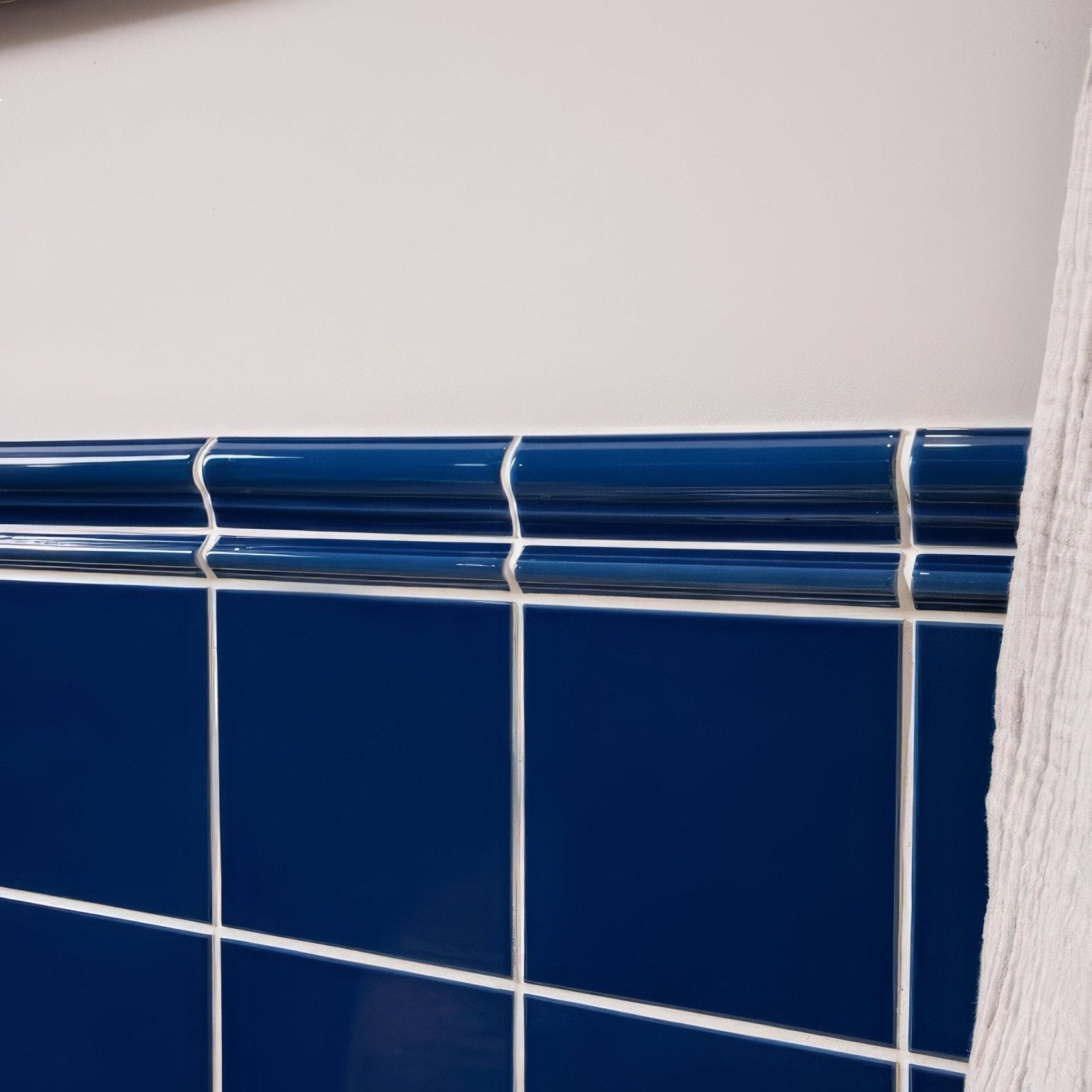 Deep blue ceramic tile border with glossy finish and white grout lines from Windsor blue field tile collection
