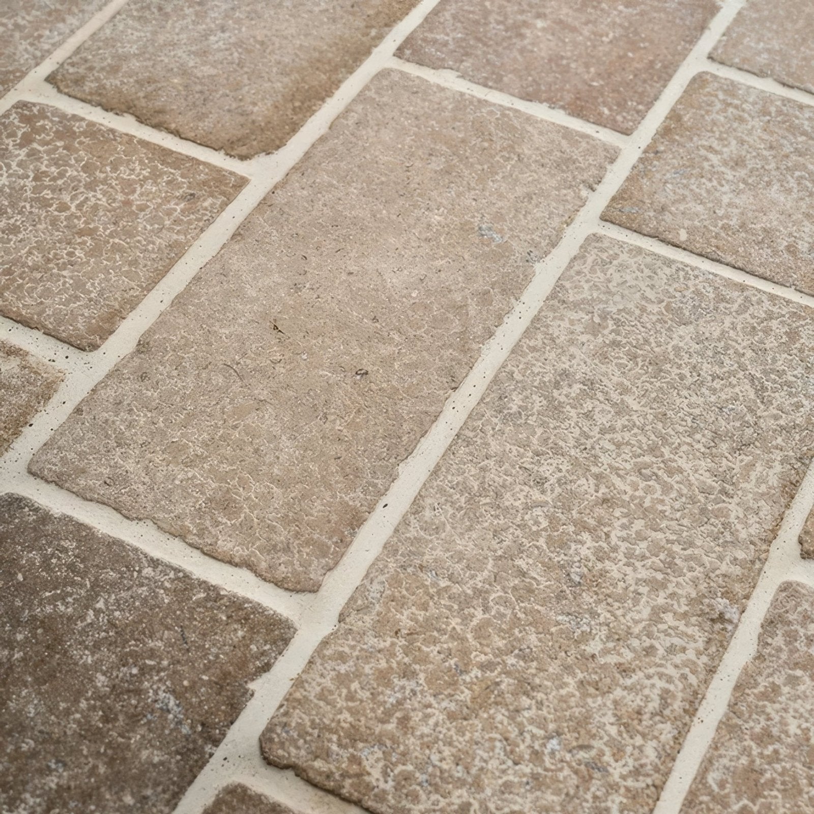 Beige rectangular wychwood limestone tumbled and etched cobble tiles with textured rustic surface and white grout lines
