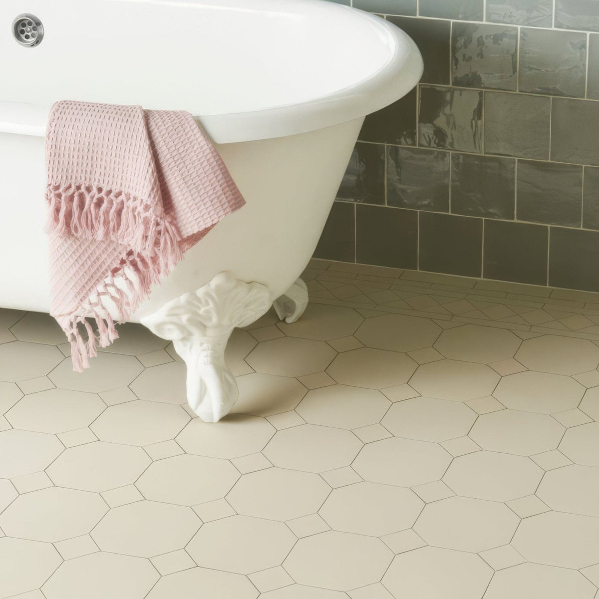 A soft pink waffle-weave towel with fringed edges draped over a white york dover clawfoot bathtub