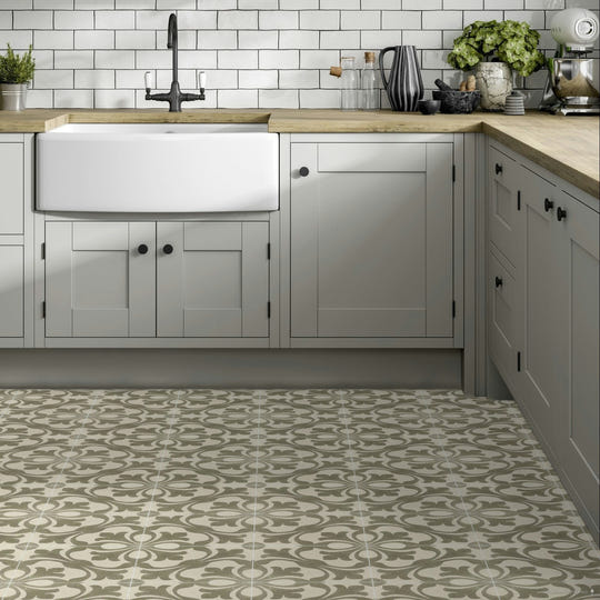 White farmhouse sink with black faucet set into light wood countertop featuring zayda sage matt vitrified ceramic tile