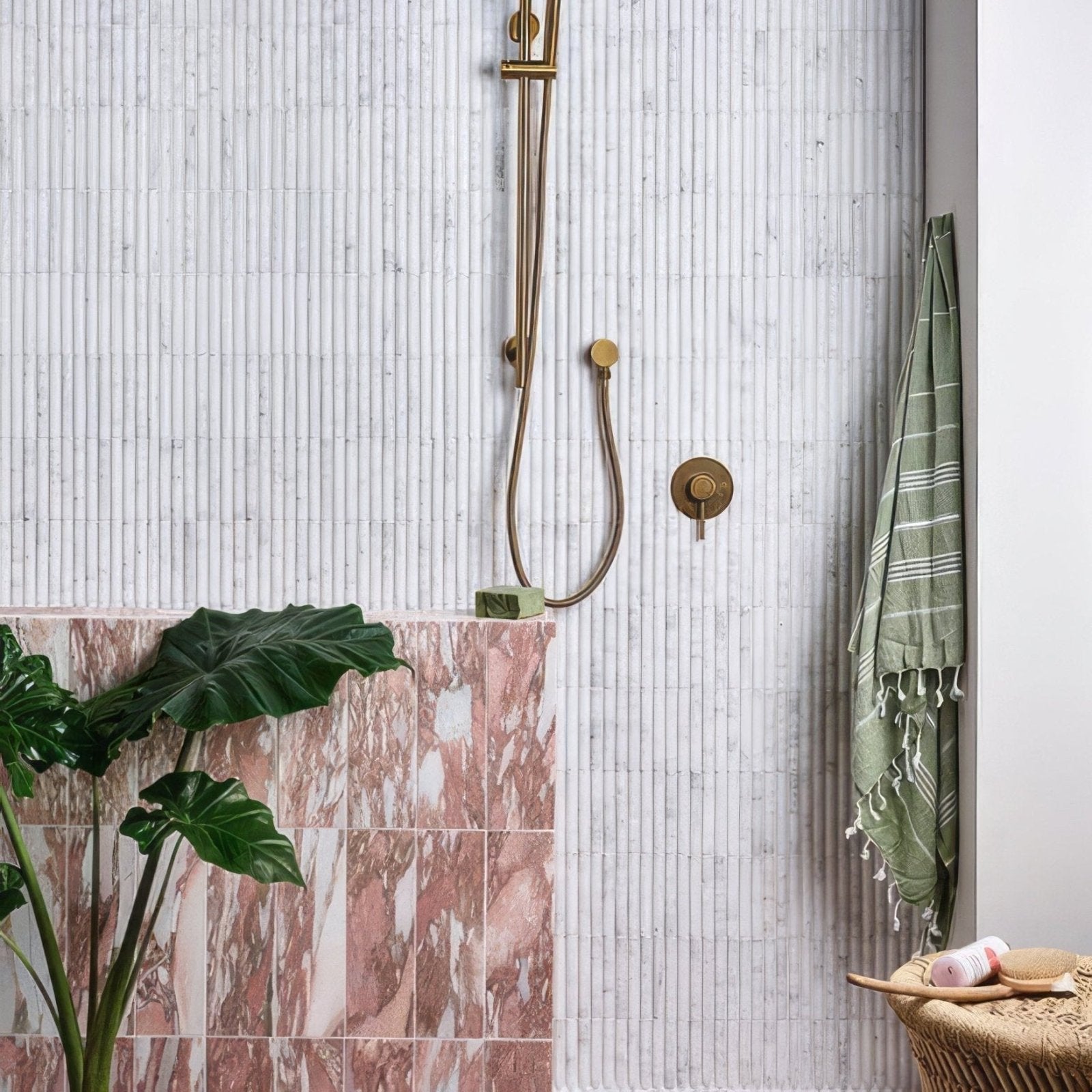 Gold-toned shower fixture with sleek curved hoses against white marble tiles in zen marble reed mosaic design