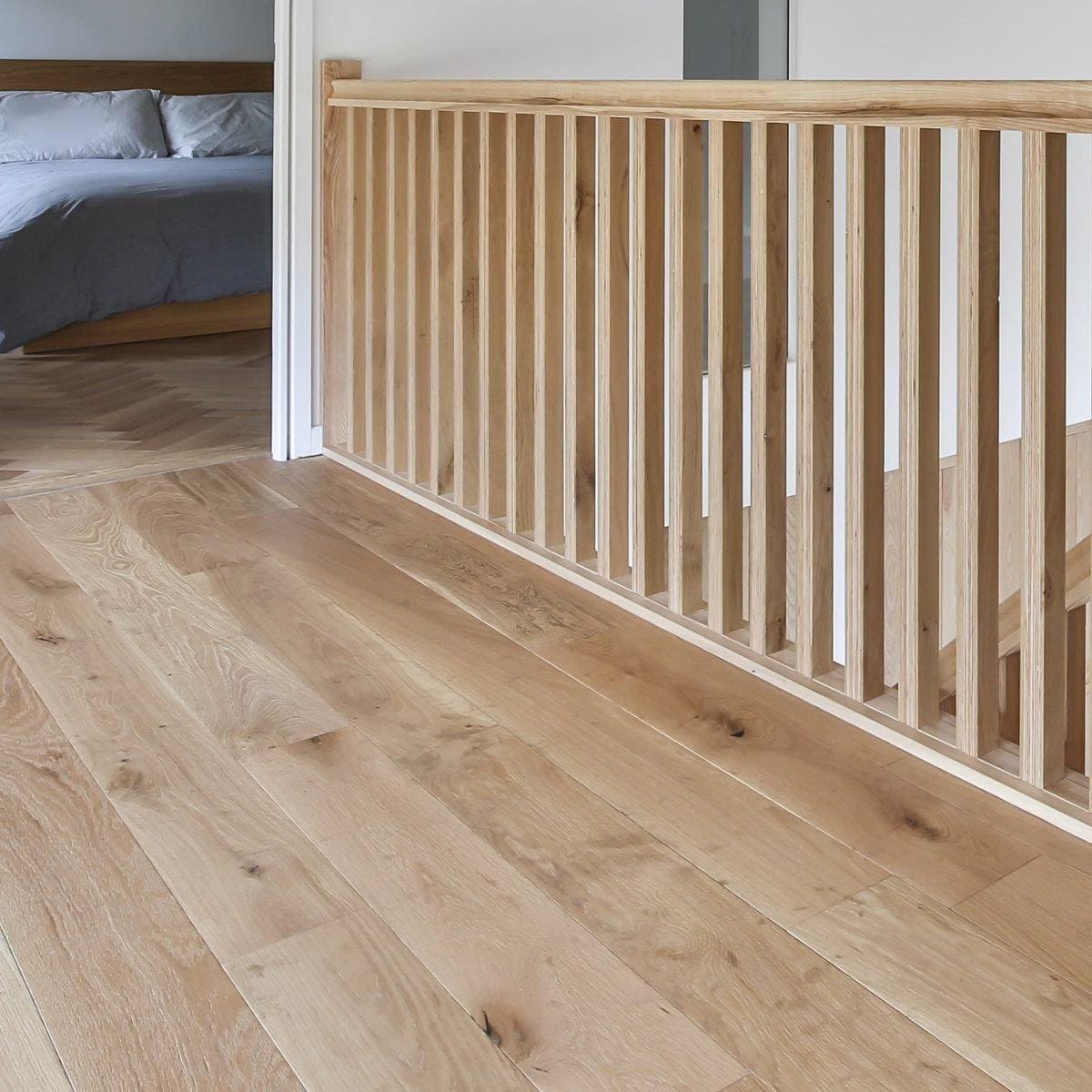 Light-colored Alpine oak rustic brushed and oiled wooden staircase railing with vertical slats and matching handrail