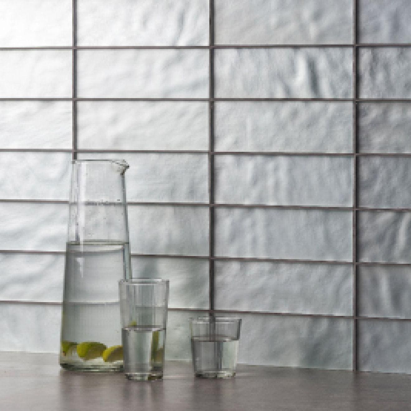 Amalthea Eclipse clear glass pitcher filled with water and lime slices beside two matching glasses