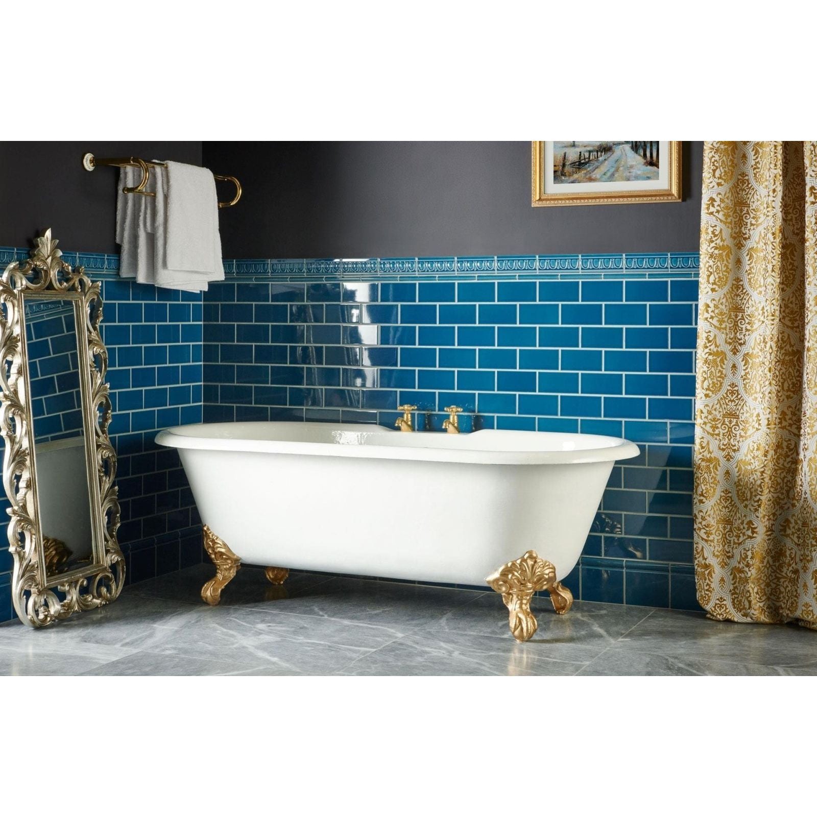 White clawfoot bathtub with gold toned ornate feet and fixtures paired with baroque blue skirting tile