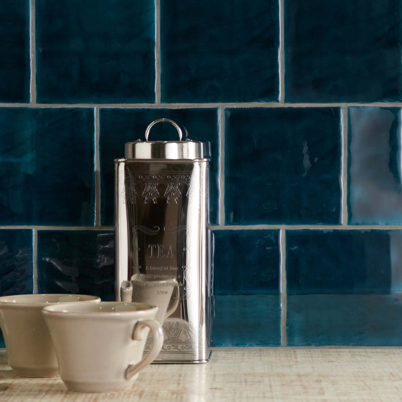 Silver metallic tea canister with engraved floral patterns and a handle on top from bastille field tile collection