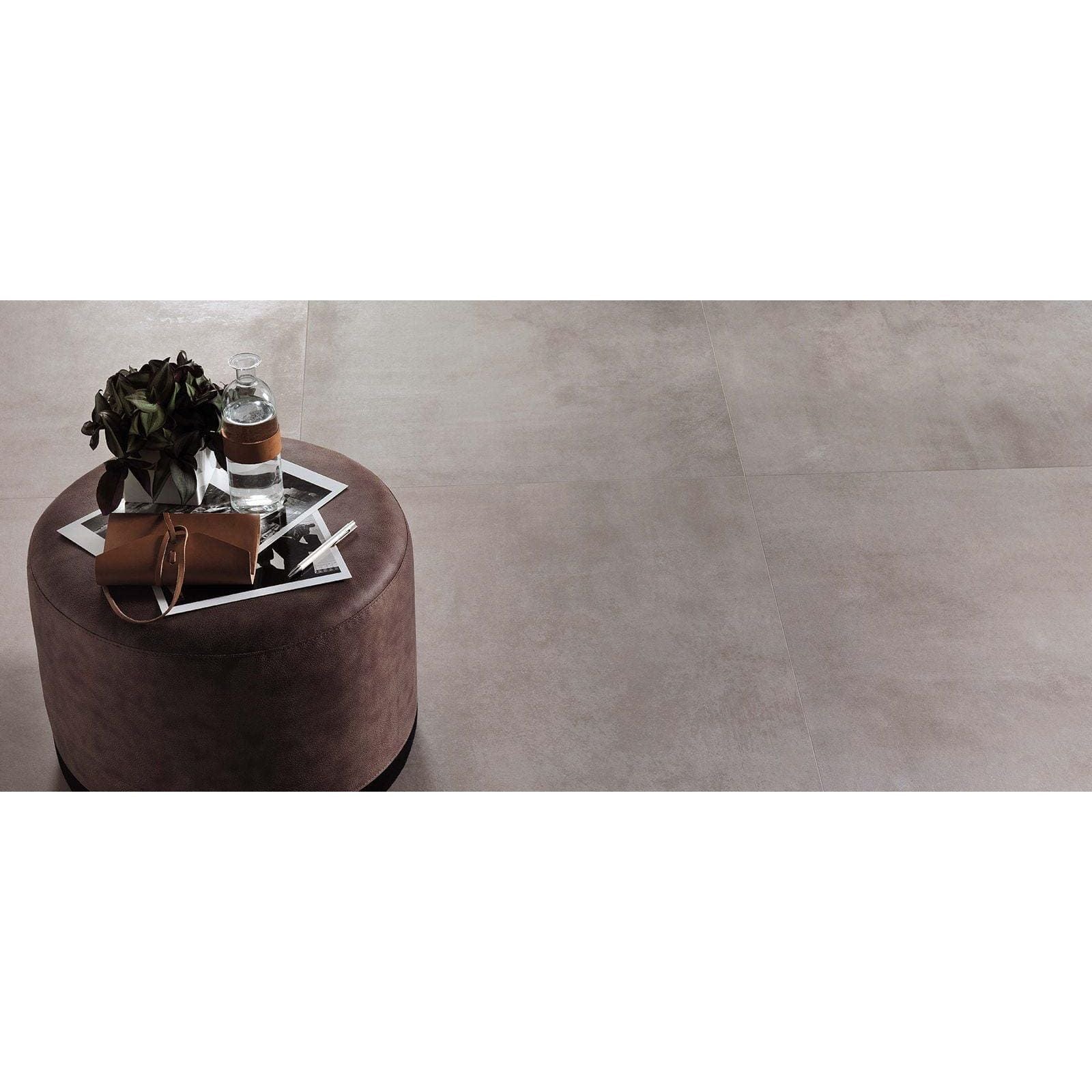 Brown leather clutch bag with silver zipper and handle resting on round Boost Pearl Matt 60 x 60cm ottoman