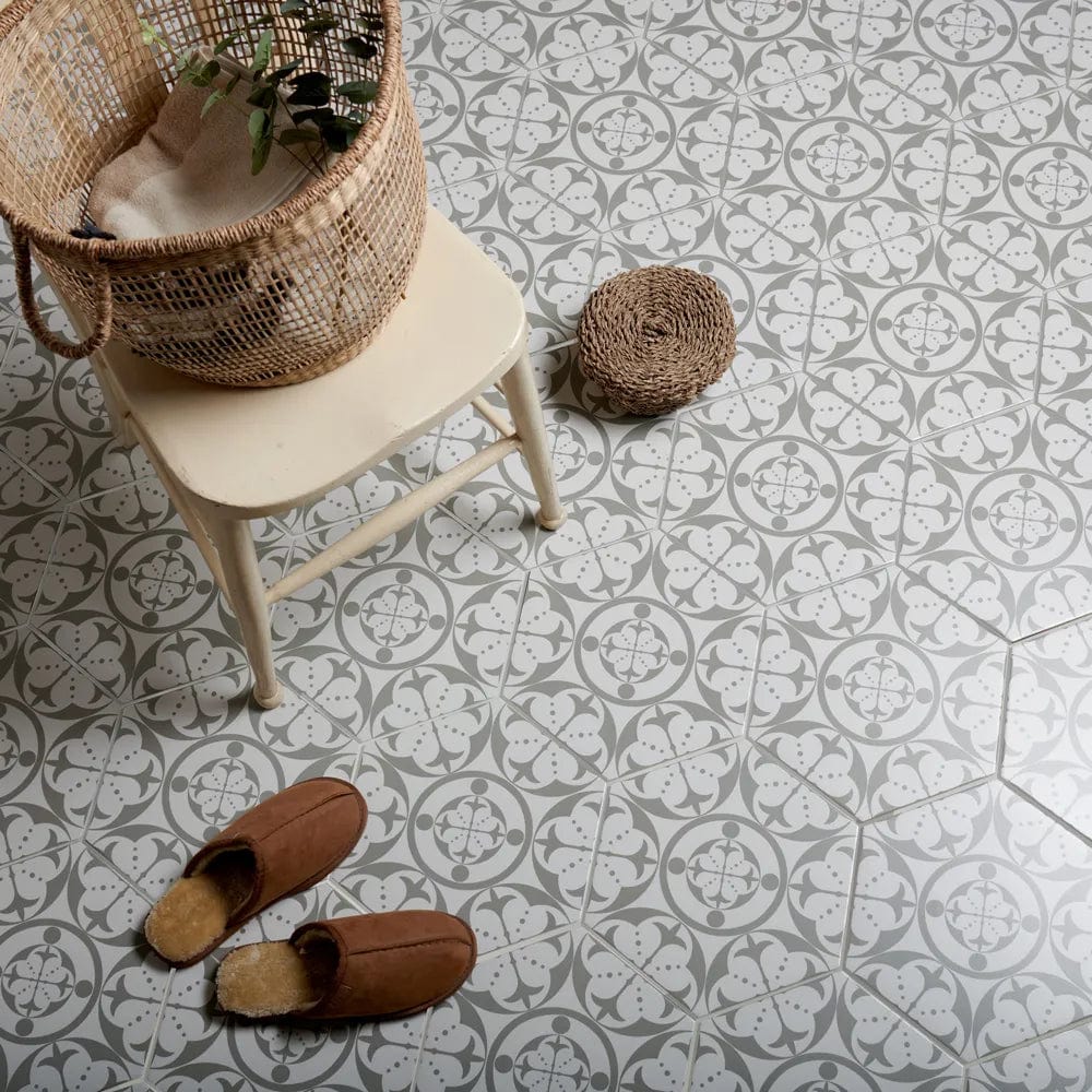 Carnaby Hexagon Grey grey and white floral hexagon tiles with a wooden chair and wicker basket