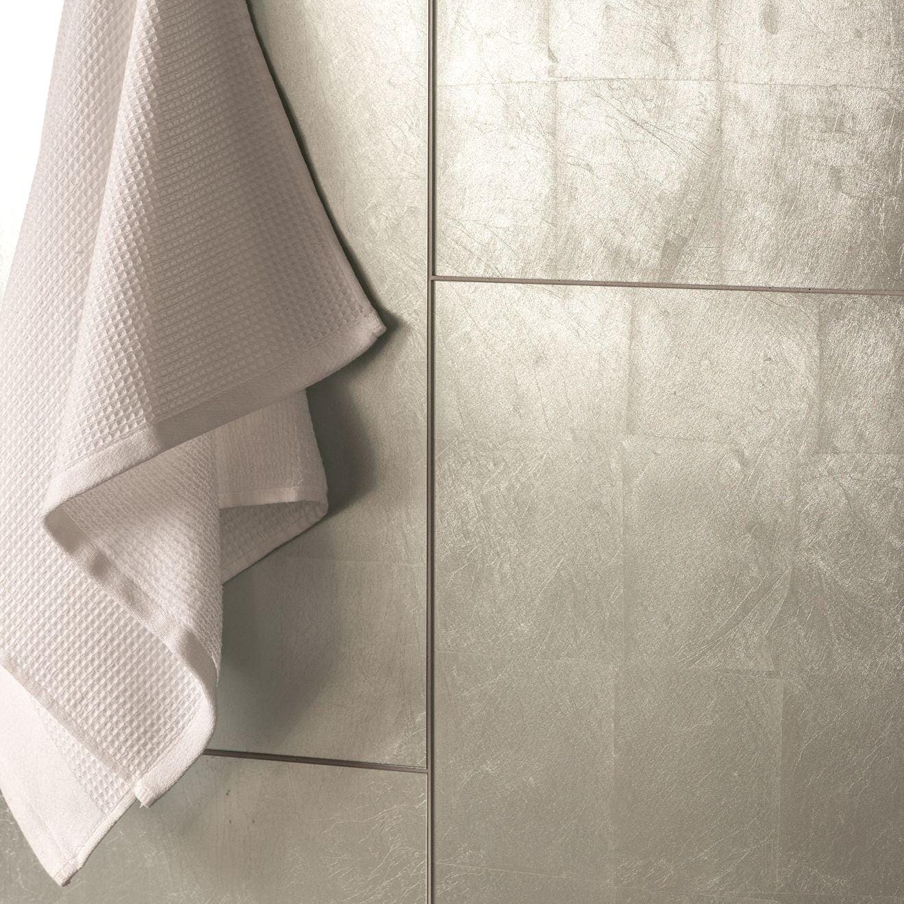 Karnak Decorative Glass silver metallic glass tiles with a white waffle towel