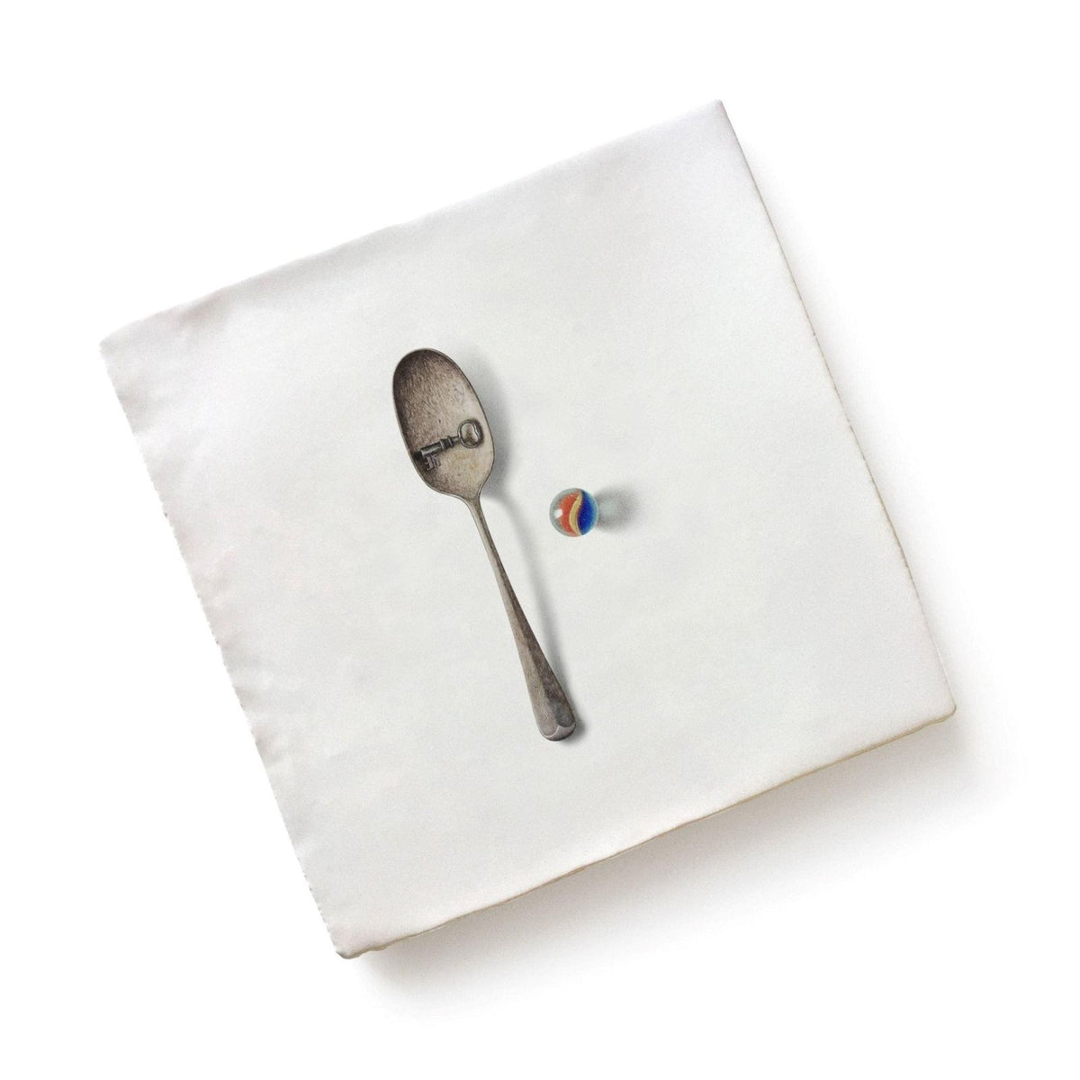 Menagerie ceramic silver spoon with key design on bowl resting beside multicolored glass marble by michael angove