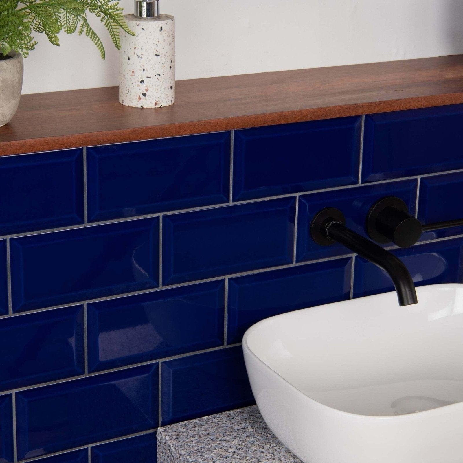 Deep blue glossy metro cobalto subway tiles with white grout lining a bathroom wall