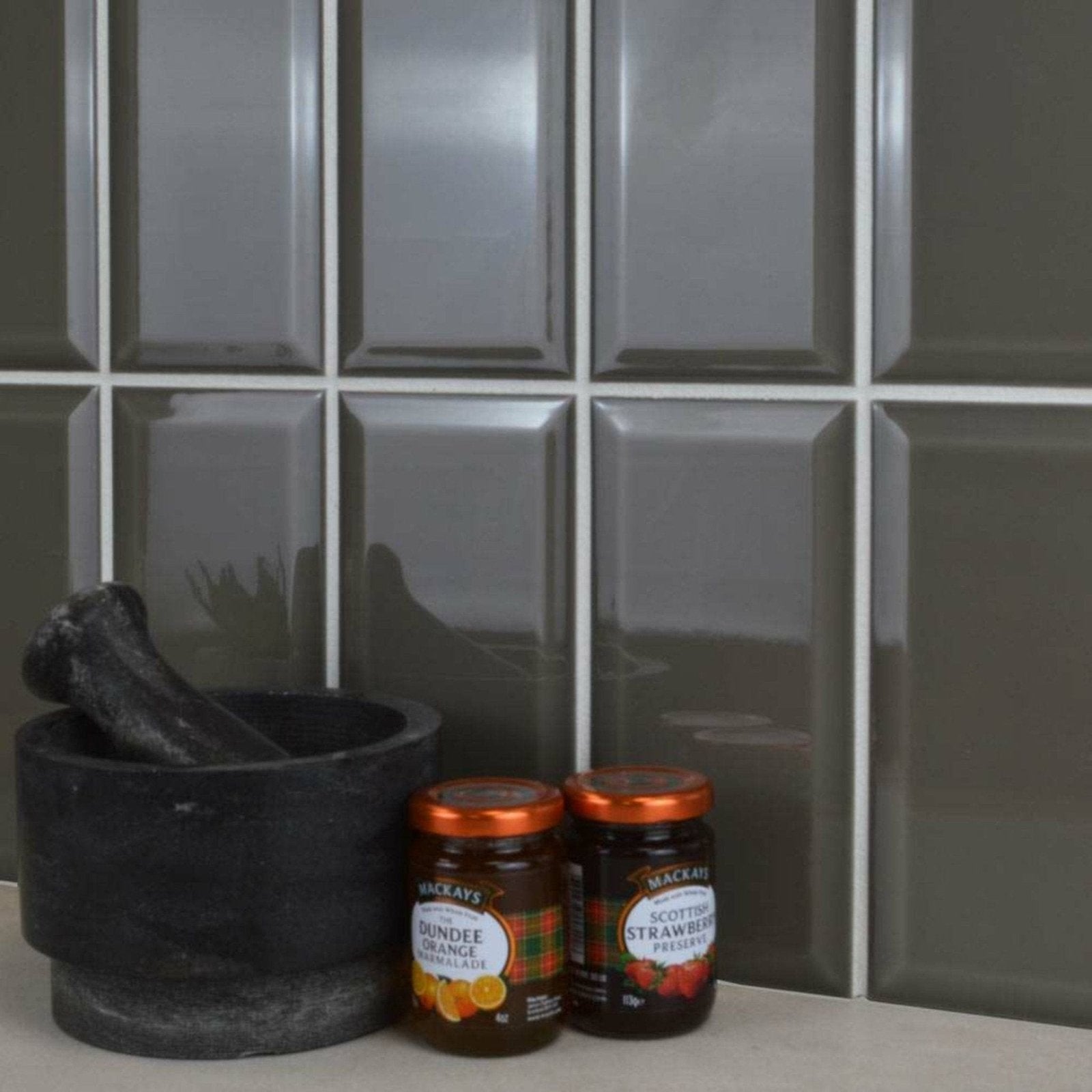 Two glass jars of mackays jam with copper lids on a metro dark grey gloss surface featuring orange marmalade and strawberry preserves