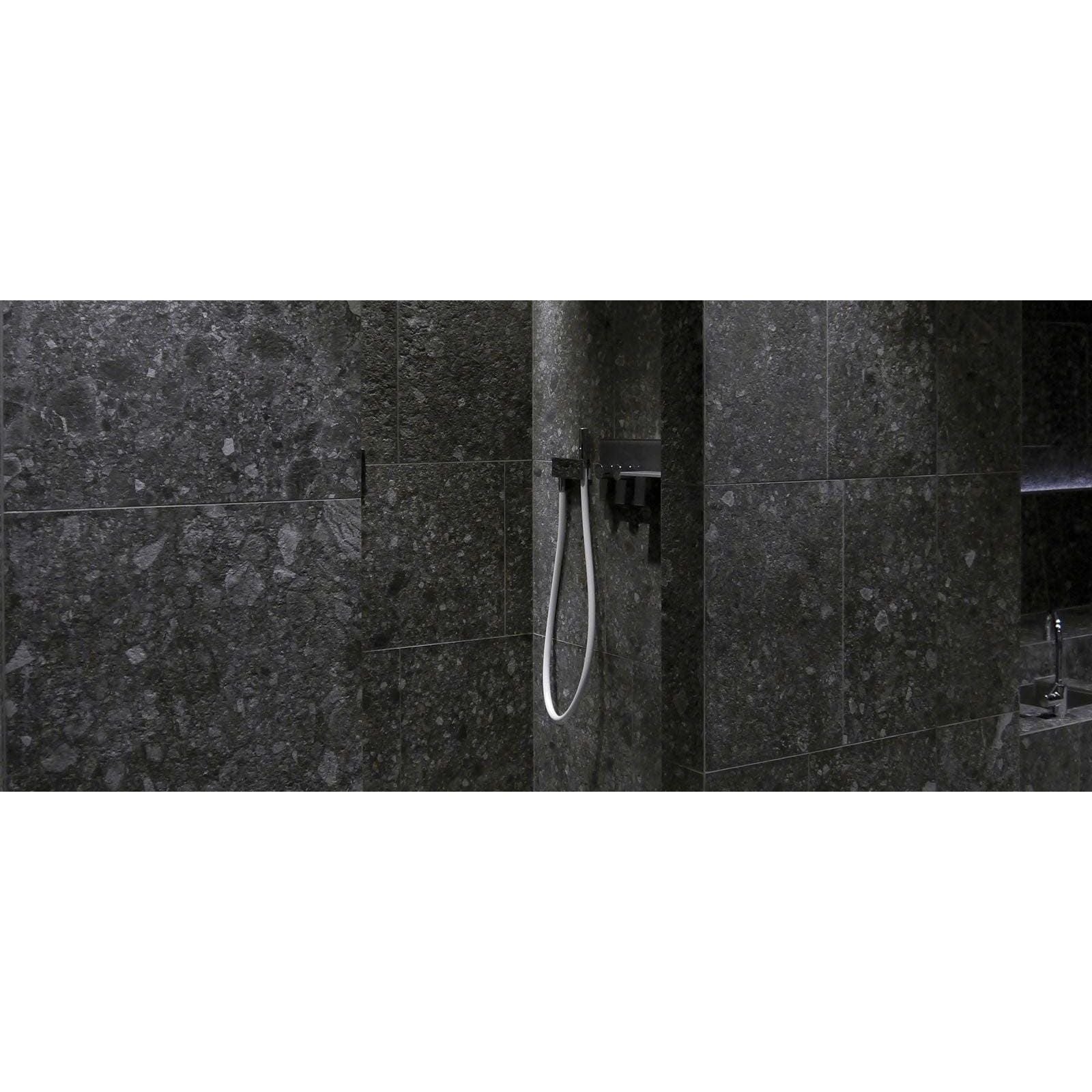 Norway Svart Matt dark grey terrazzo-effect tiles with a black showerhead