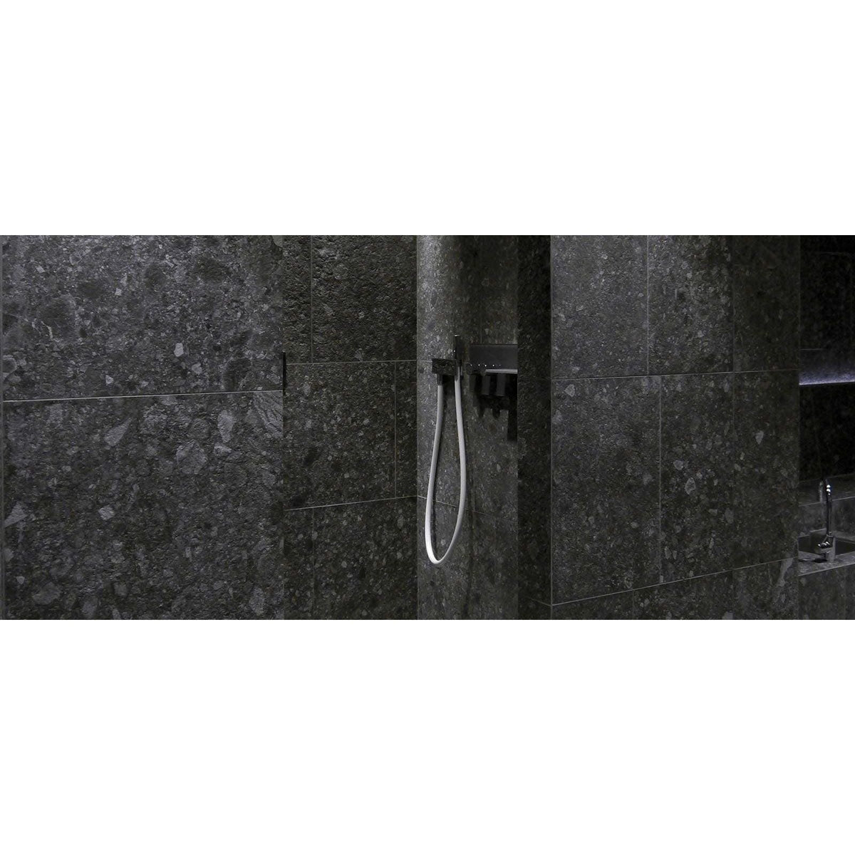 Norway Svart Matt dark grey terrazzo-effect tiles with a black showerhead