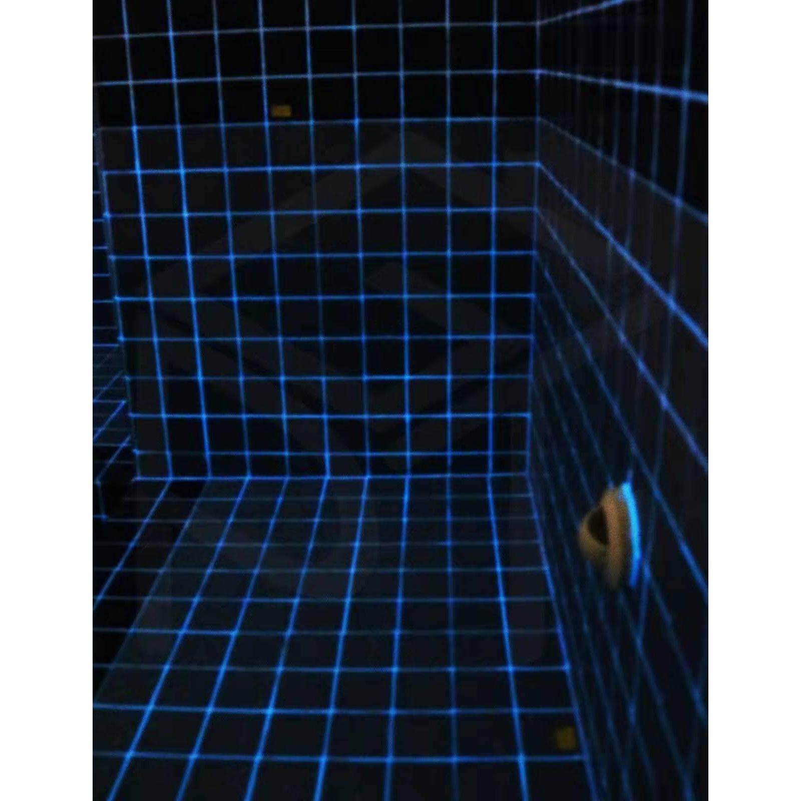Blue grid-patterned tiled bathroom wall featuring a small circular drain fixture in perflex p30 luminous blue