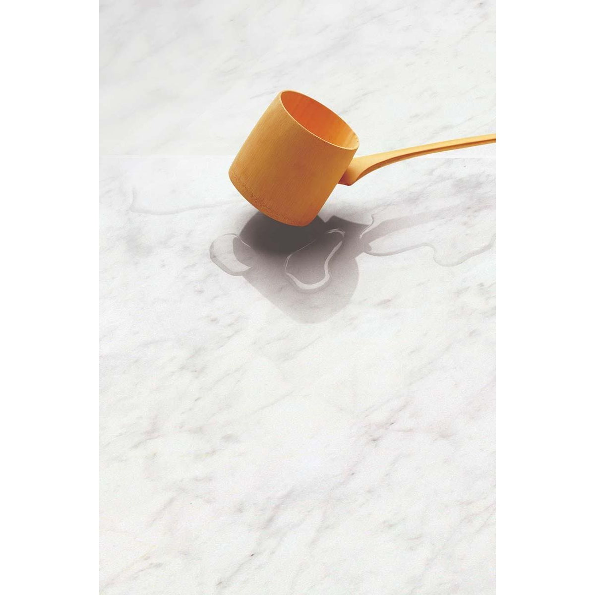 Python Carrara Porcelain Gloss white marble-effect tiles with a mustard wooden ladle