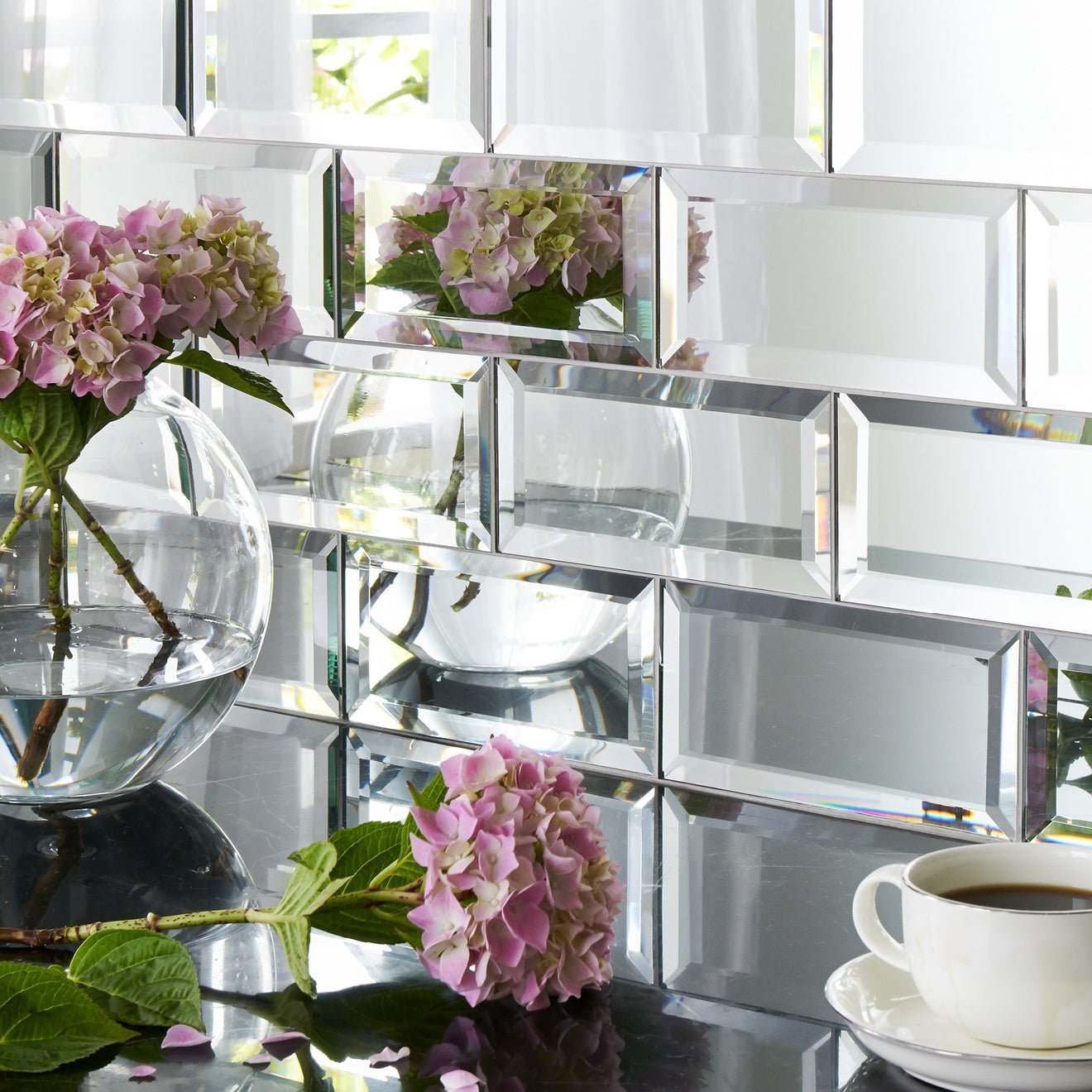 Silver mirror bevel clear glass spherical vase holding pink hydrangeas for elegant floral display