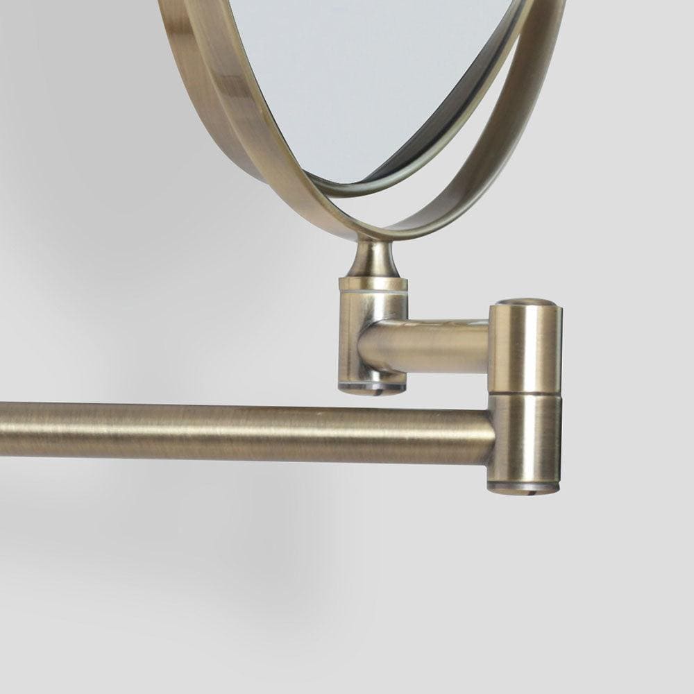 A sleek brushed brass double-sided taylor reversible 5x magnifying wall mirror with a modern articulated arm