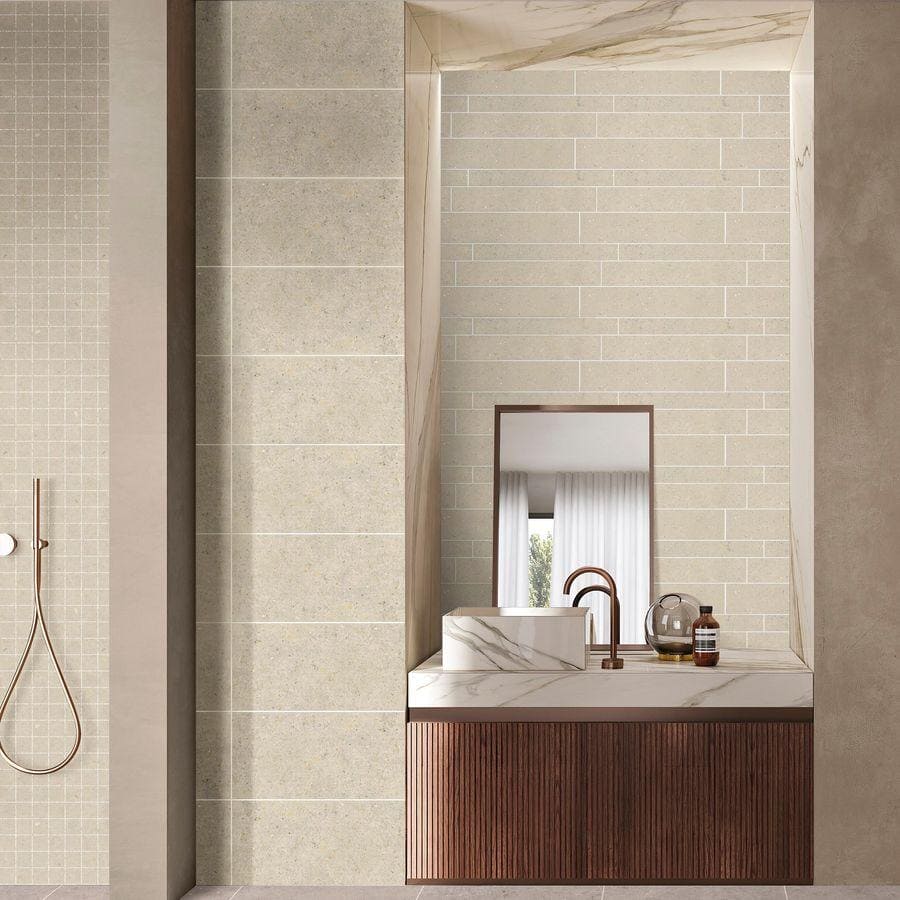 A sleek white marble vessel sink with gray veining on a wooden vanity featuring terrazzo coolstone white tiles