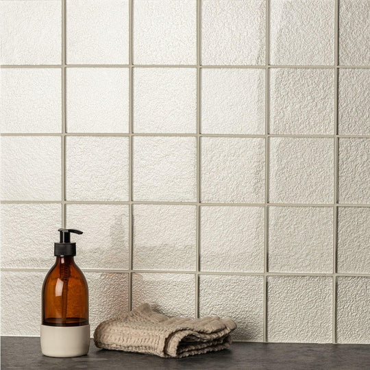 Triton Metallica Glass cream metallic glass tiles with a soap dispenser and towel