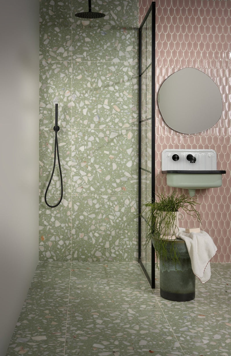 The bathroom features a modern shower with green and white terrazzo tiles and pink scale-patterned wall tiles.