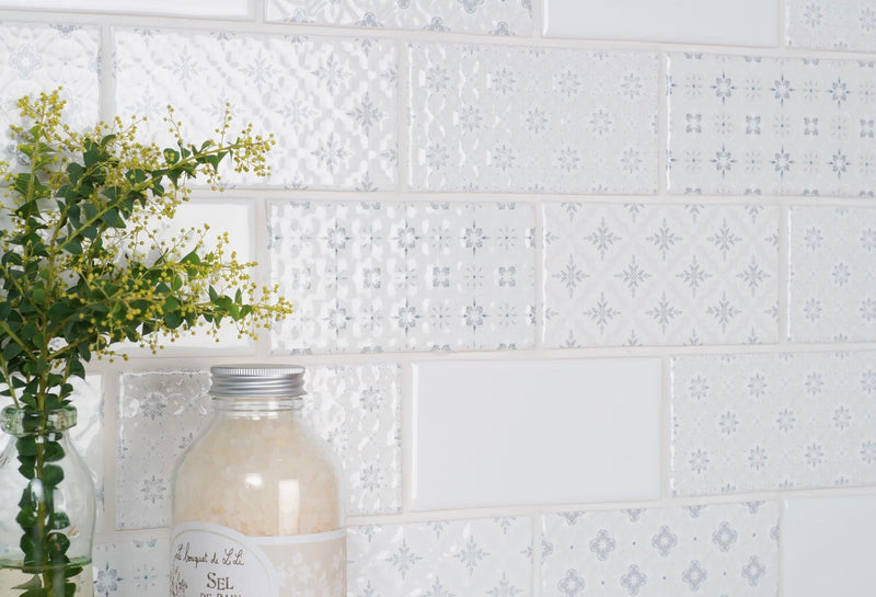 A clear glass jar with silver lid filled with light-colored salt labeled sel highlighting mosaic backsplash style