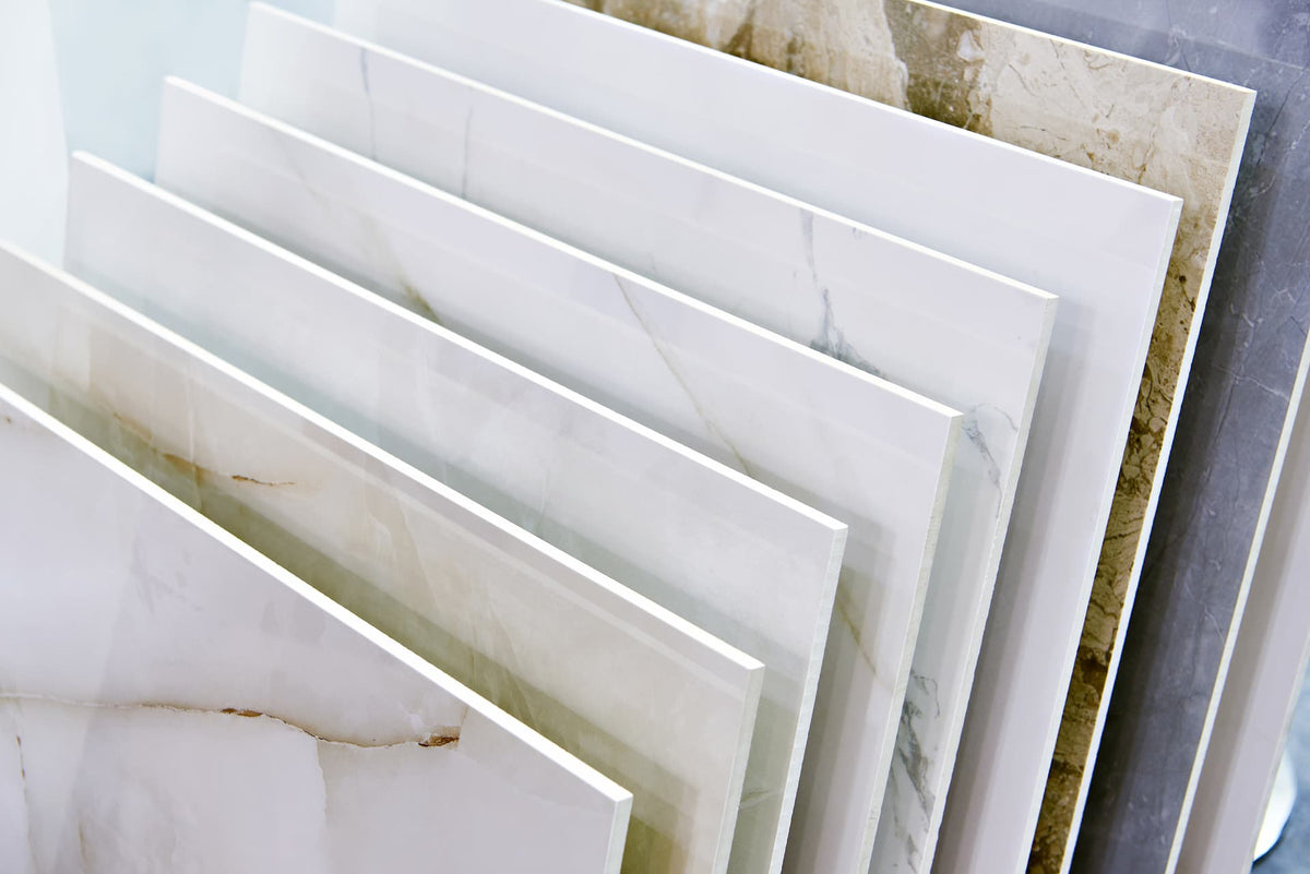 Stacked porcelain tiles with white and beige marble veining and a glossy finish for flooring and walls in porcelain vs ceramic tiles article
