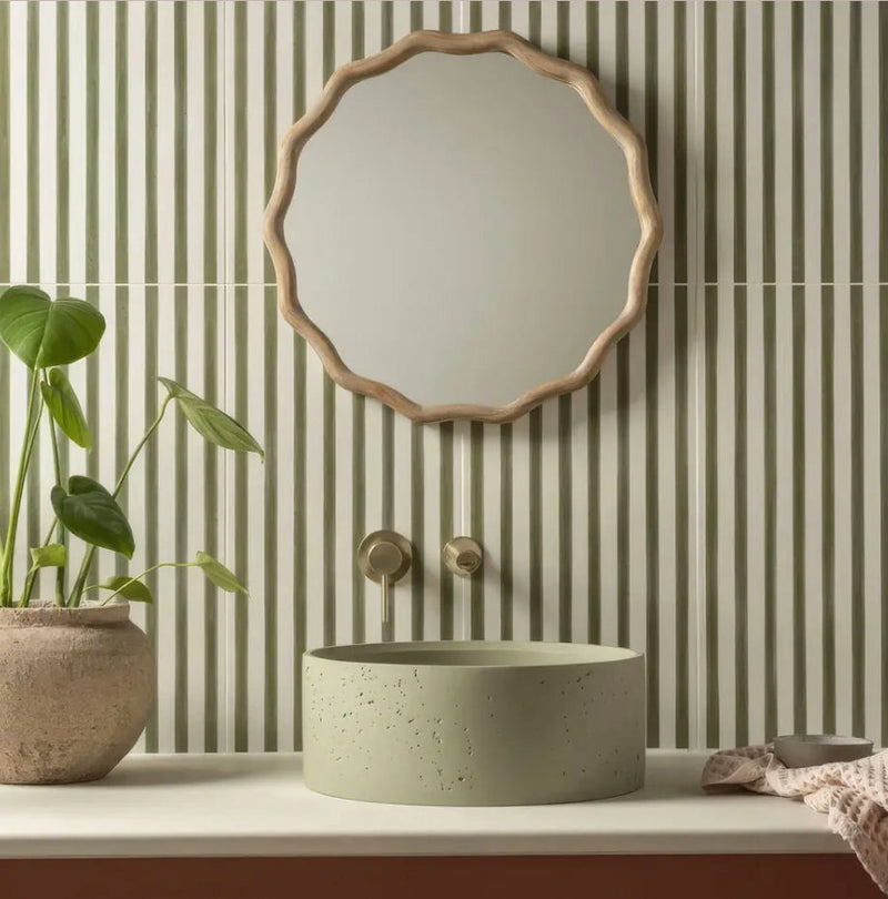 A round light green concrete sink with speckled texture on a white countertop from the promenade collection