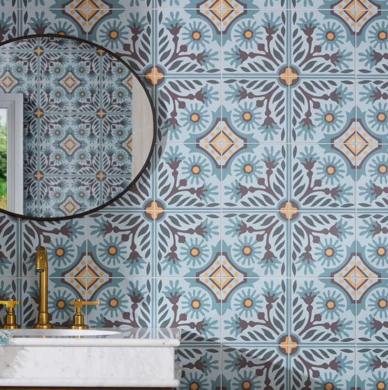 Blue and beige patterned porcelain tiles with floral and geometric designs covering a bathroom wall in Indirah Porcelain collection