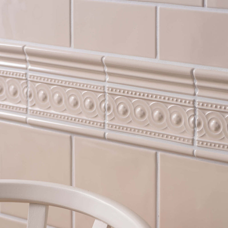 Beige ceramic tile border with raised oval and dot patterns from the artisan baroque moulding collection
