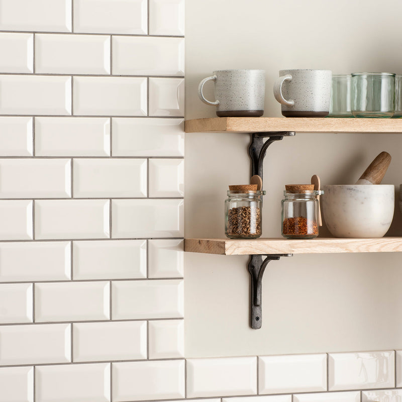 Two speckled gray ceramic mugs with dark brown rims on light wood shelf in artworks 3x3 metro bevelled tile collection