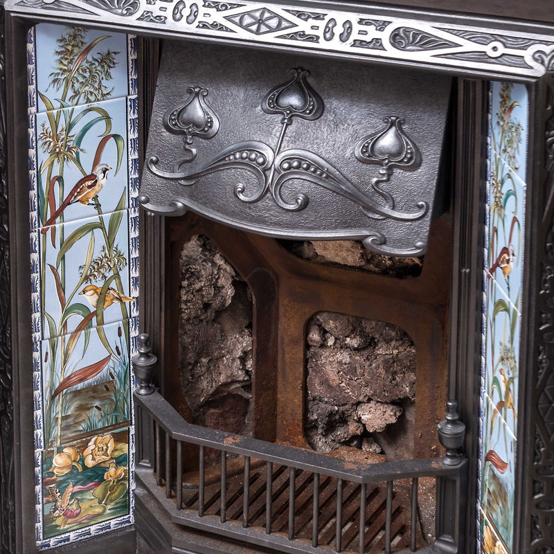 Antique black iron fireplace insert with ornate silver decorative panel and colorful botanical tile panels from artworks birds and butterfly 5-tile collection