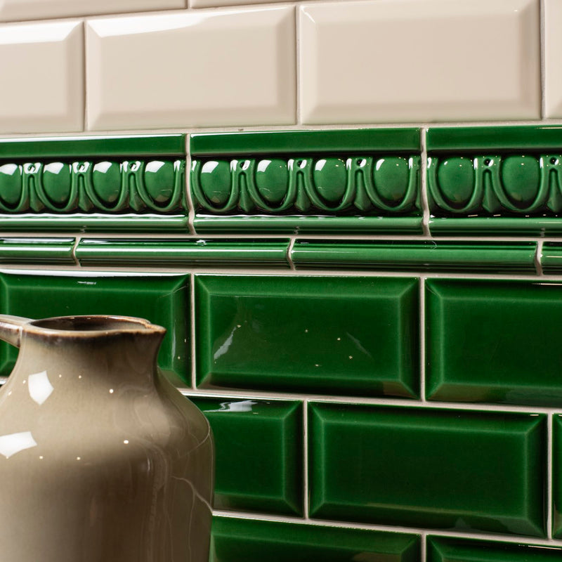 Deep green ceramic subway tiles with a glossy finish and embossed decorative egg and dart moulding border