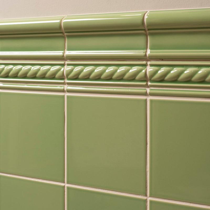 Light green ceramic tile with glossy finish and decorative rope-like molding above square tiles from artworks rope moulding collection.