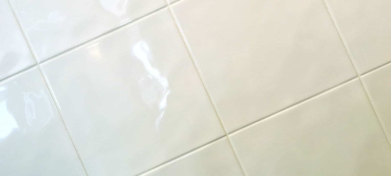Beige square ceramic tiles with glossy finish and visible grout lines from the branco collection
