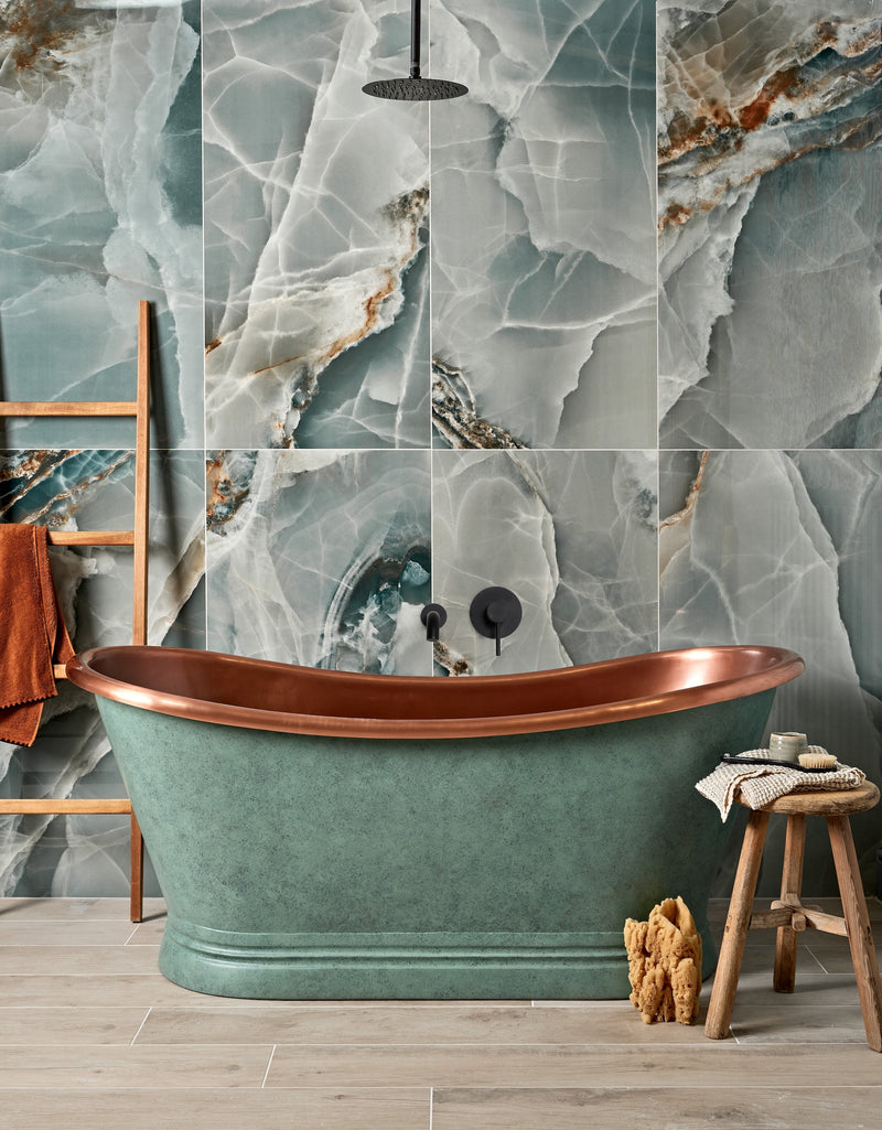 A freestanding copper and teal green oval bathtub with a polished metallic rim from the Hollywood Porcelain collection
